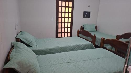 a room with two beds and a door with a window at Casa com 2 quartos em excelente localização in Juazeiro do Norte