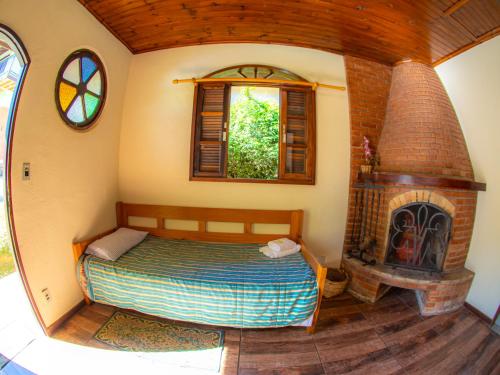 a bedroom with a bed and a brick fireplace at Villa da Vila Montanhas in Monte Verde