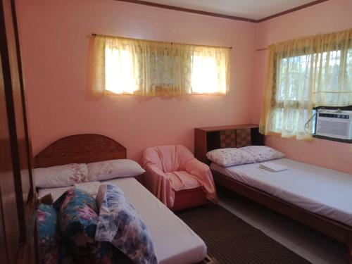 a room with two beds and a chair and two windows at Ancestral BATO in Bato