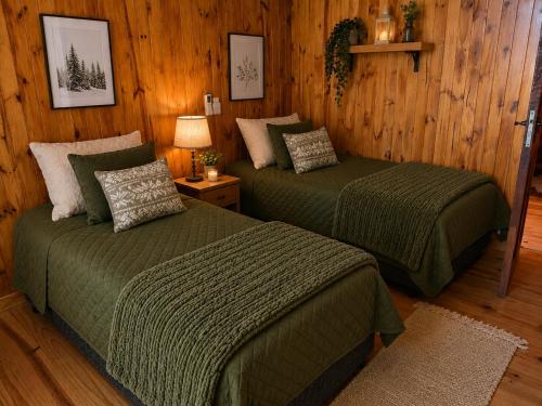 two beds in a room with wooden walls and wooden floors at Cozy Premium Delta Cabin Private Dock in Tigre