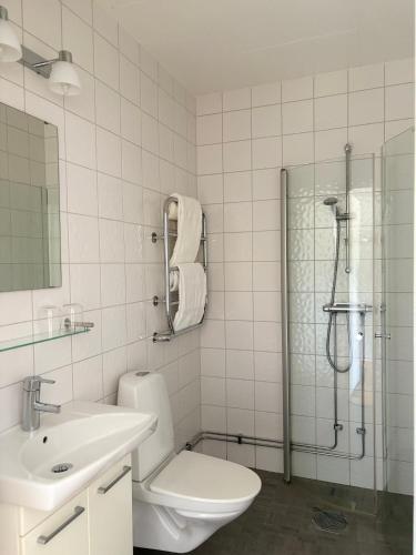 a bathroom with a shower and a toilet and a sink at Närebo Gårdshotell in Lidköping