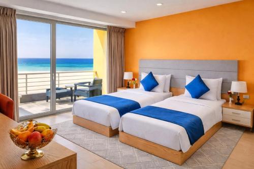two beds in a hotel room with a view of the ocean at Bosaso Airport Hotel in El Ad