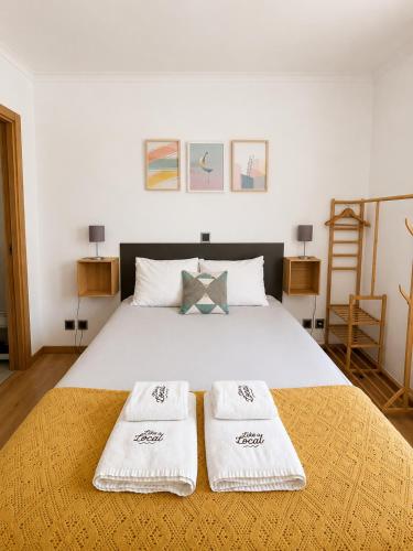 a bedroom with a bed with two white towels on it at Like a Local Guest House in Ericeira