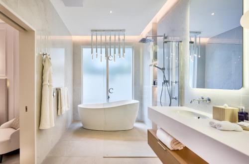 a white bathroom with a tub and a sink at Calabash Hotel in Saint Georgeʼs