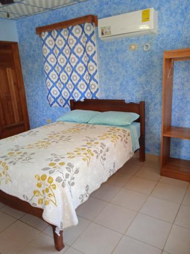 a bed in a room with a blue wall at Sunrise Inn in Puerto Armuelles