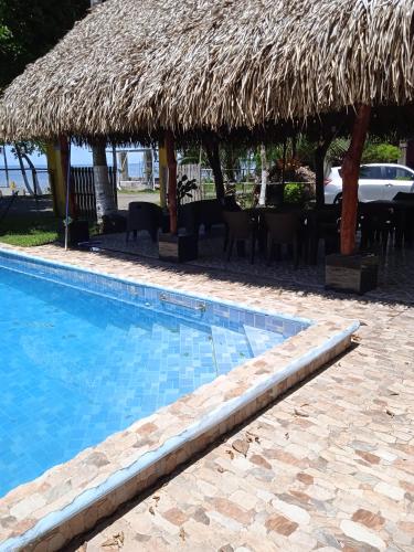 a swimming pool with a straw umbrella and a table and chairs at Sunrise Inn in Puerto Armuelles