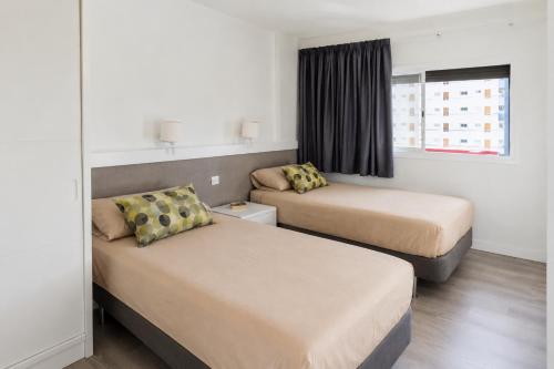 a hotel room with two beds and a window at Gran Rapido - Modern 1 bedroom apartment very close to Yumbo in Playa del Ingles