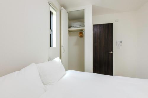 a bedroom with two white beds and a brown door at AsobiStay児玉藤 in Nagoya