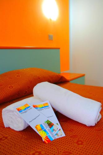 a pair of towels and a book on a bed at Turas Club Case Vacanze in Bosa