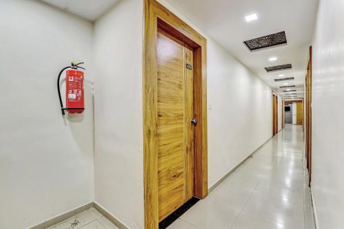 a hallway with a wooden door and a white wall at Hotel O Maple view in Naroda