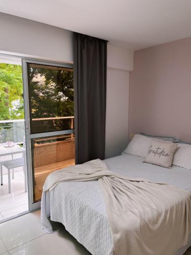 a bedroom with a bed and a large window at Prédio Solar do Atlântico, apt 204 - Apartamento lateral em Tambaú in João Pessoa