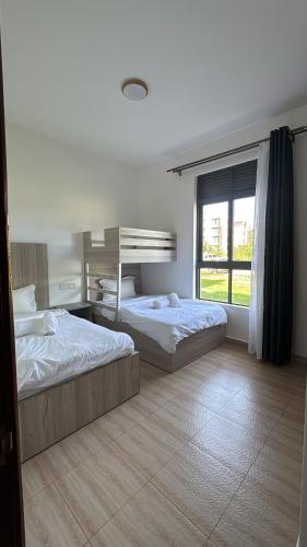 a bedroom with two beds and a window at Pearl Escape in Entebbe