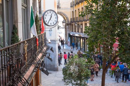 people walking down a street with a clock on a building at Petit Palace Posada del Peine in Madrid