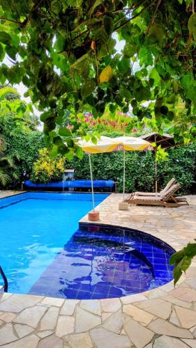 an umbrella and chairs next to a swimming pool at Recanto das Termas, Chalés in Termas do Ibirá