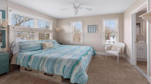 a bedroom with a bed and a chair and windows at Summer Winds Sanctuary in Cape May