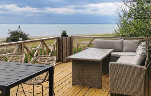 a wooden deck with a table and a couch at Nice Home In Øster Assels in Øster Assels