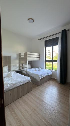 a bedroom with two beds and a window at Pearl Escape in Entebbe