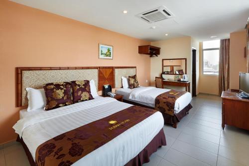 a hotel room with two beds and a television at Terra Nova Hotel in Melaka