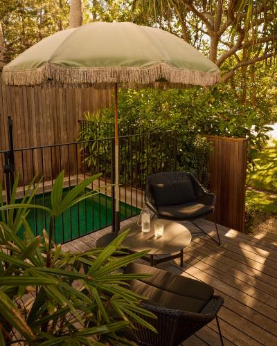 a patio with an umbrella and a table and chairs at 28 Degrees Byron Bay - Adults Only in Byron Bay