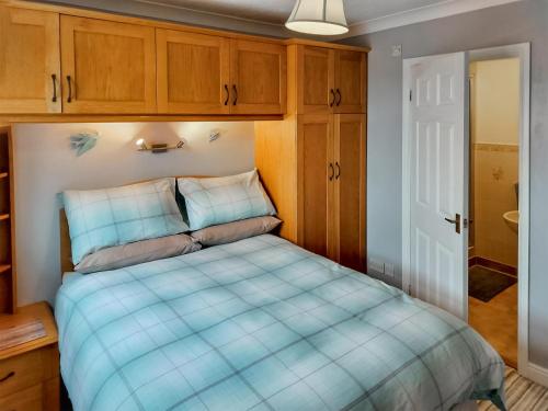 a bedroom with a blue bed with wooden cabinets at Brompton Lodge in Ganton