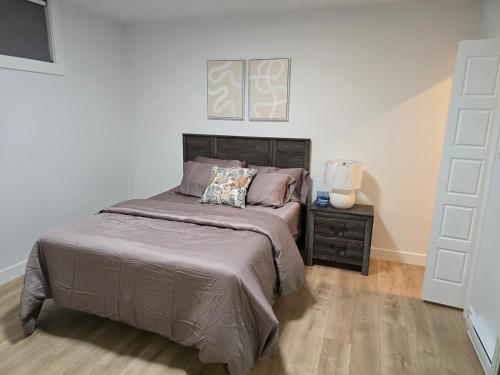 a bedroom with a large bed and a night stand at Serene luxury apartment in Moncton