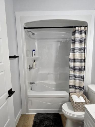 a white bathroom with a tub and a toilet at Serene luxury apartment in Moncton