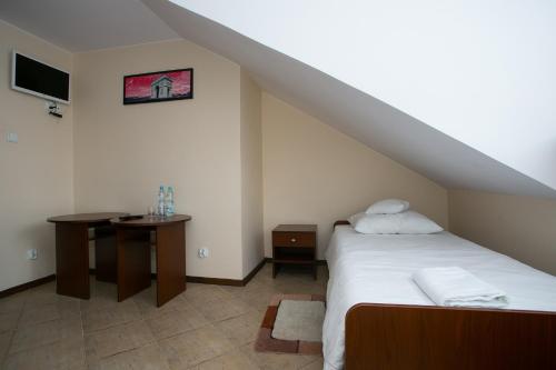 a bedroom with a bed and a table and a tv at Labirynt in Łomża