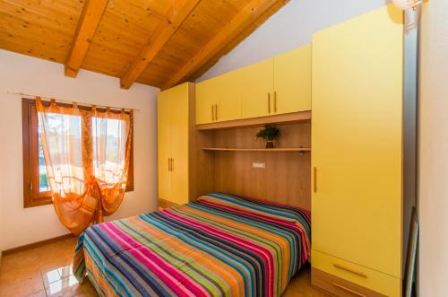 a bedroom with a bed with a colorful striped blanket at Residence Borgo Stella Marina in Bibione