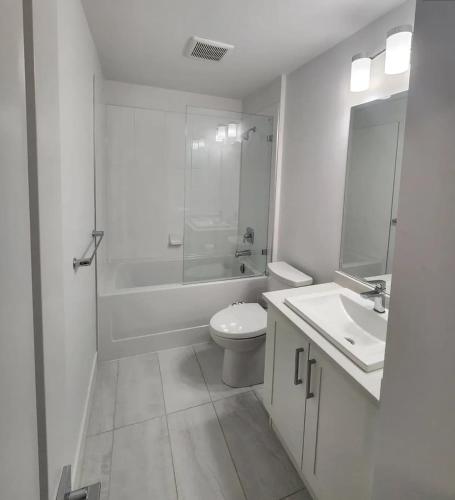 a white bathroom with a toilet and a sink at Mountain Views, Premium Coquitlam Stay, Minutes to Transit in Coquitlam