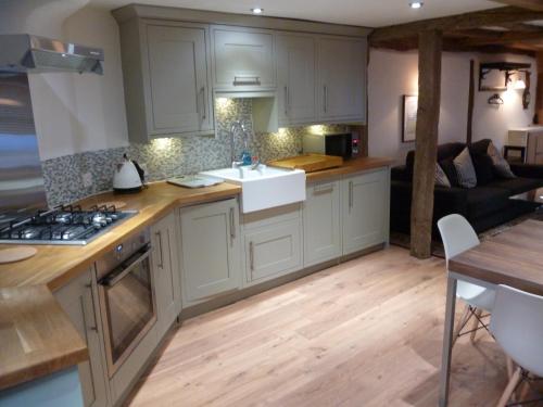 a kitchen with white cabinets and a living room at Kings Cottage in Wokingham