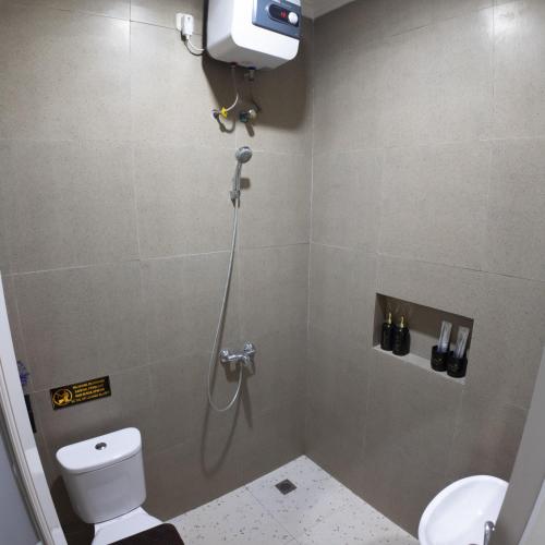 a bathroom with a shower with a toilet and a shower at The Marytara Residence in Sawah