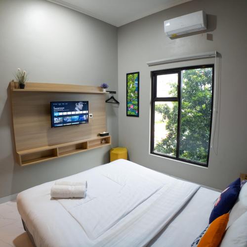 a bedroom with a bed and a tv on the wall at The Marytara Residence in Sawah