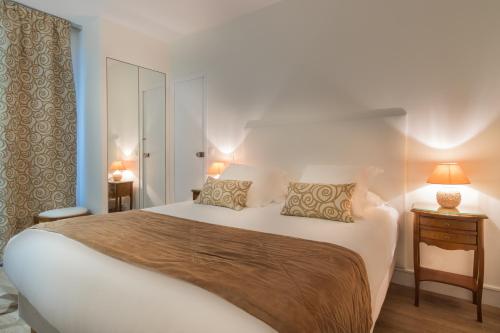 a bedroom with a large white bed with two pillows at Arcadie Montparnasse in Paris