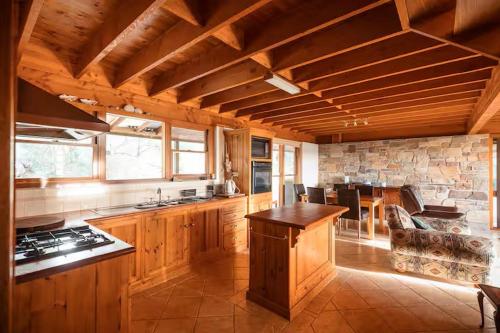 a large kitchen with wooden cabinets and a stone wall at Possum Ridge in Muston
