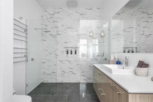 a white bathroom with a sink and a shower at The Jetty, Port Willunga in Port Willunga