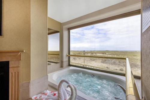 a bath tub in a room with a large window at Best Western Plus Ocean View Resort in Seaside