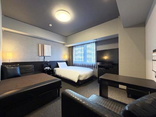 a hotel room with a bed and a couch at Hotel Route-Inn Grand Ota Ekimae in Ota