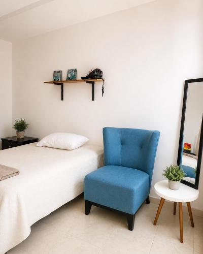 a bedroom with a bed and a blue chair at Casa Mayi Private house with pool in Chablekal in Chablekal