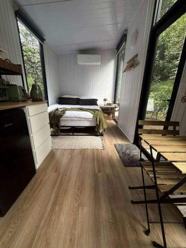 a bedroom with a bed in a room with wooden floors at Secret Garden by Tiny Away in Uki
