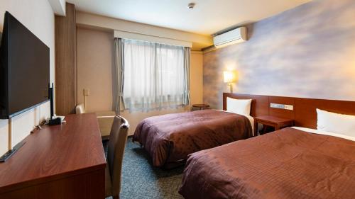 a hotel room with two beds and a flat screen tv at Hotel Resh Tottori Ekimae in Tottori