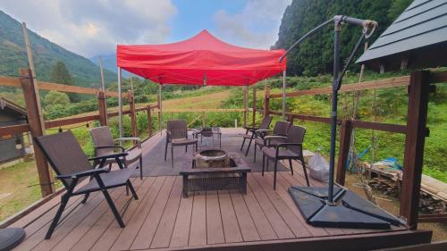 a deck with chairs and a table and a red umbrella at ペルセウス座流星群の体験 Villa Dottaru 土樽の自然に囲まれた大人の秘密基地 in Yuzawa