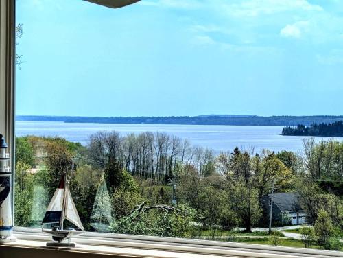 a window with a view of a lake and a sailboat at Bayside Waterview Cottage in Ellsworth