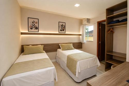 a bedroom with two beds and a shelf at Hotel Elevare Niteroi in Niterói