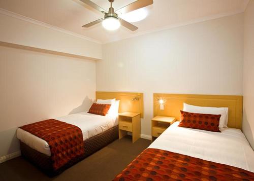 a hotel room with two beds and a ceiling fan at Hibernian Hotel in Beechworth