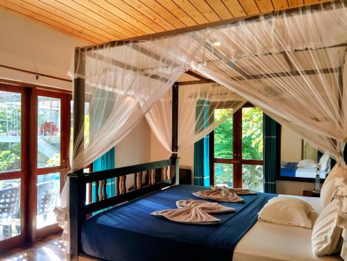 a bedroom with a canopy bed with two towels on it at Leisure Land in Galle