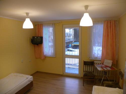 Habitación con cama, TV y ventanas. en Pokoje Gościnne Standard, en Jastrzębia Góra