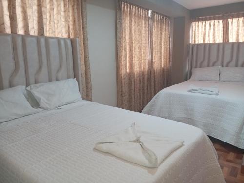a bedroom with two beds with white sheets at Hospedaje San Isidro in Cali