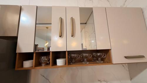 a white cabinet with cups and wine glasses on it at Casa Luxo & Conforto com 4 camas e 2 quartos completa in Juazeiro do Norte