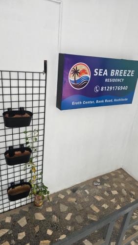 a sign on a wall with plants on a shelf at Sea Breeze Residency in Kozhikode