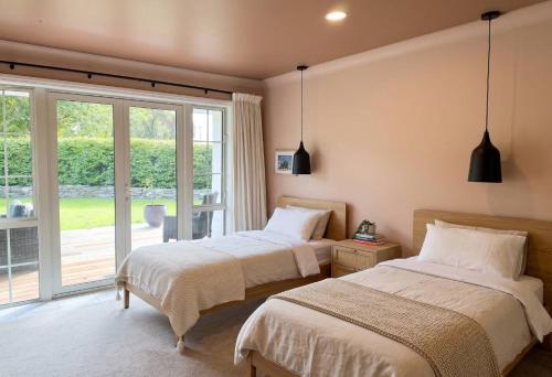 two beds in a room with a large window at The Orchard Escape - Cromwell in Cromwell